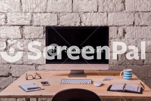 Desk With Various Gadgets And Office Supplies. Computer, Smart Phone And Stationery Around The Workplace. White Brick Wall.